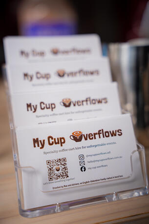 Keep our details handy! Scan to book My Cup Overflows for your next Adelaide gathering. A stack of business cards displaying the My Cup Overflows logo and a QR code.