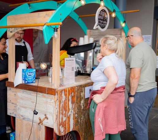 Fast, friendly service that keeps the lines moving and your guests happy. Customers standing at a rustic wooden coffee cart waiting for their beverage orders.